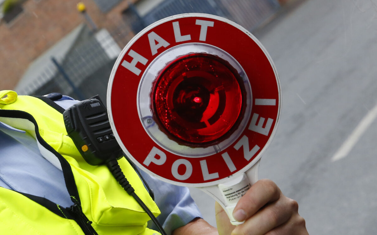 Ein Polizist hält eine Kelle hoch bei einer Kontrolle Ein Polizist hält eine Kelle hoch bei einer Kontrolle